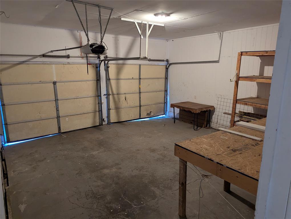 Spacious 2-car garage with overhead door, workbench, and shelving. Plenty of room for tools, projects, and storage!