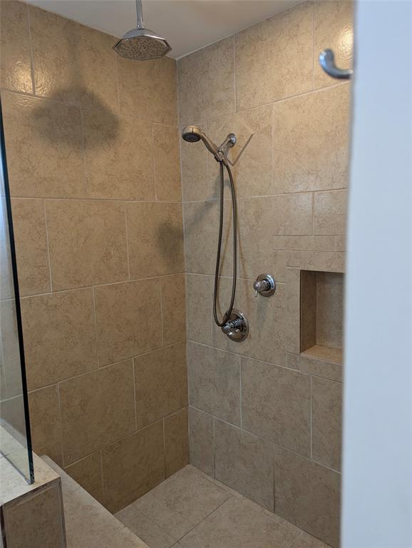 View 2: Tiled walk-in shower with built-in bench, handheld showerhead, and convenient grab bars.