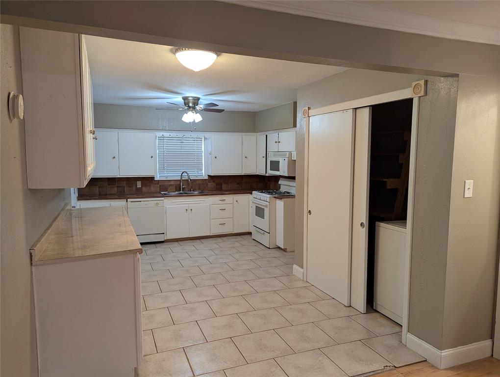 The kitchen offers tile flooring, white cabinetry, and a functional layout with potential for future updates.