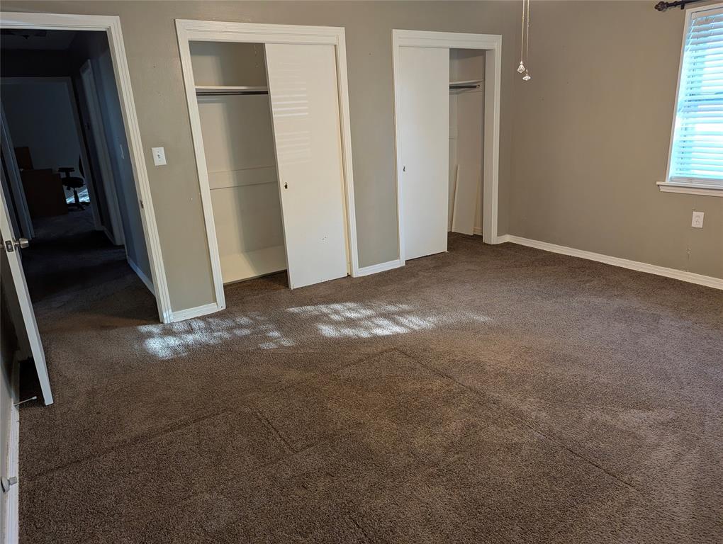 Another view of Bedroom #3, highlighting two closets, neutral wall colors, and front yard views. Flexible space for a bedroom, guest room, or home office!