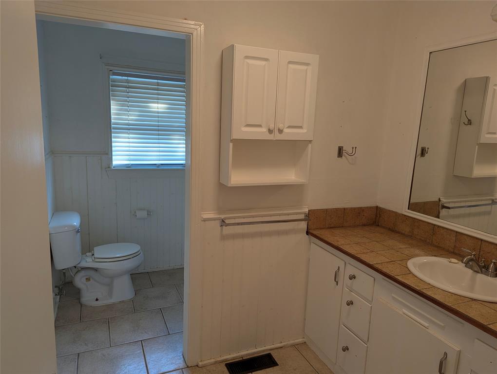 Full bathroom located between Bedrooms #2 and #3, featuring a vanity, built-in cabinetry, and an opportunity for a complete makeover.