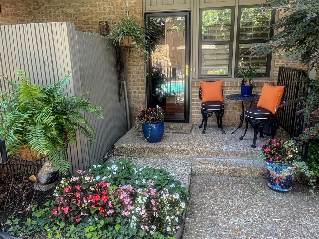 Brick exterior with a glass-paneled entry door, adjacent windows with interior shutters, and an exposed aggregate concrete patio