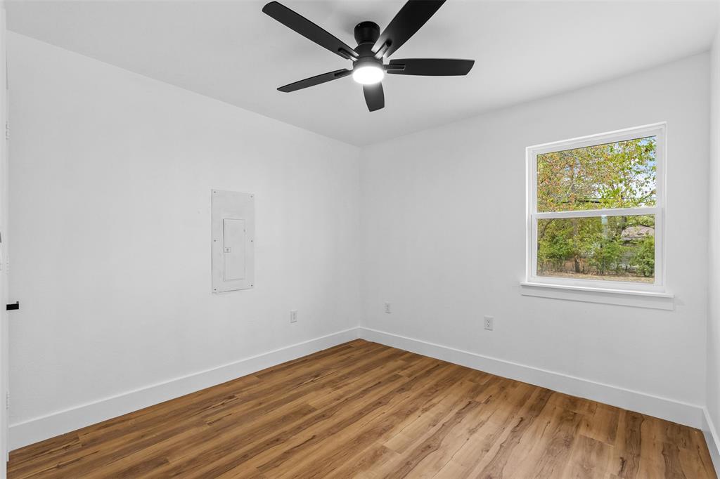 Bright room featuring wood-finish flooring, a contemporary ceiling fan with integrated lighting, and a window with white trim