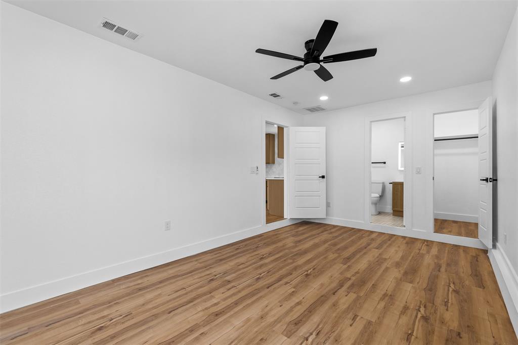 Wood-finish flooring throughout, white walls, recessed lighting, and a black ceiling fan