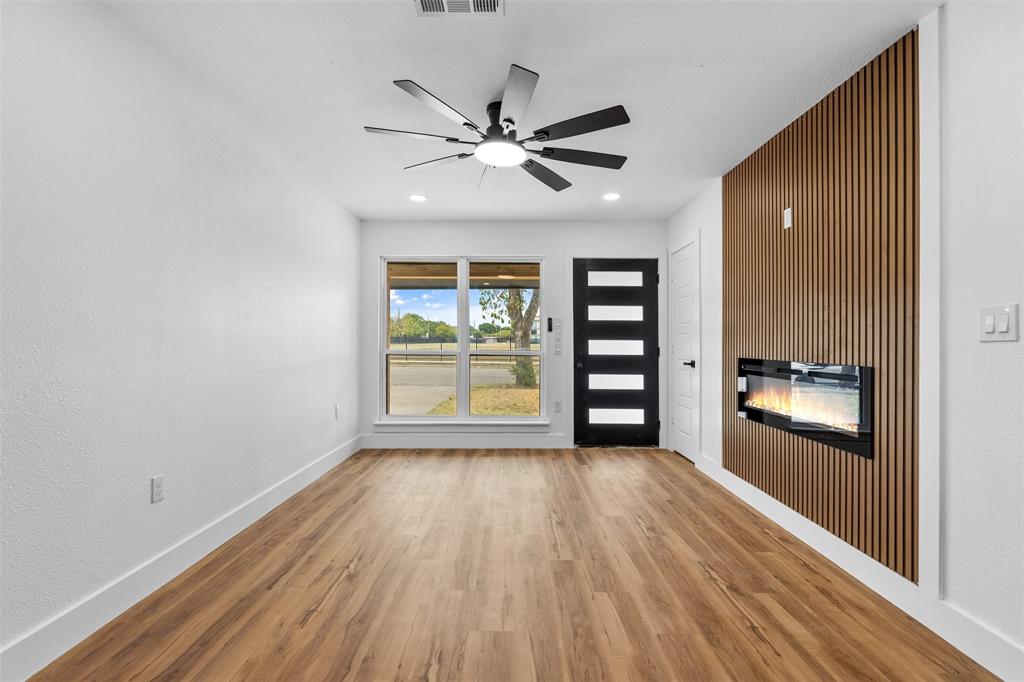Wood-finish flooring, white walls, and a modern ceiling fan with lighting Wood-finish flooring, white walls, and a modern ceiling fan with lighting