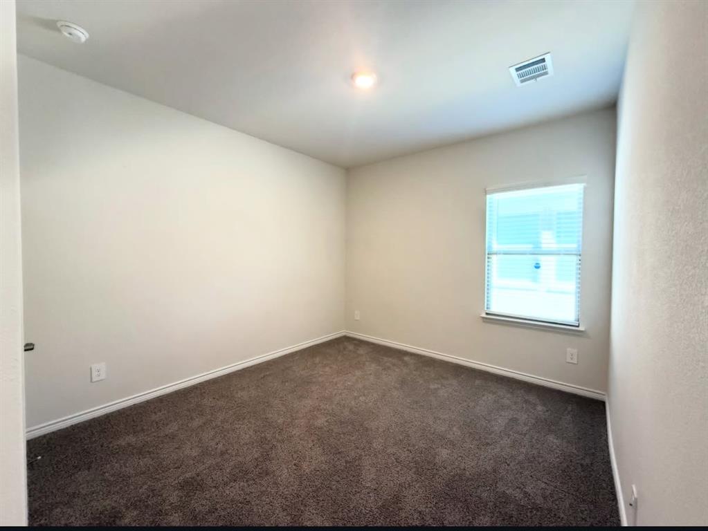 Neutral-toned walls, high ceilings, plush wall-to-wall carpeting, and a single-pane window featuring horizontal blinds
