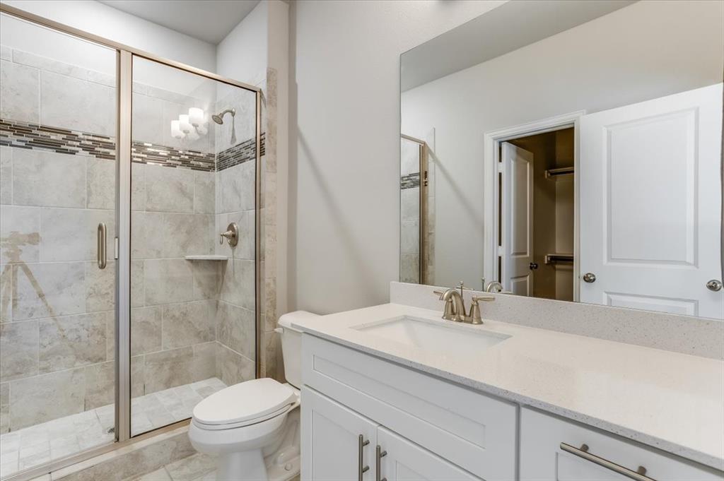 Glass-enclosed shower with tiled walls and a decorative mosaic band