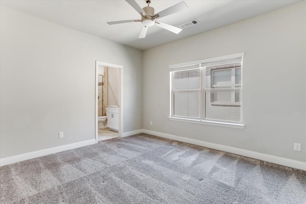 Neutral wall paint, ceiling fan, carpet flooring, window with blinds, and an adjoining bathroom