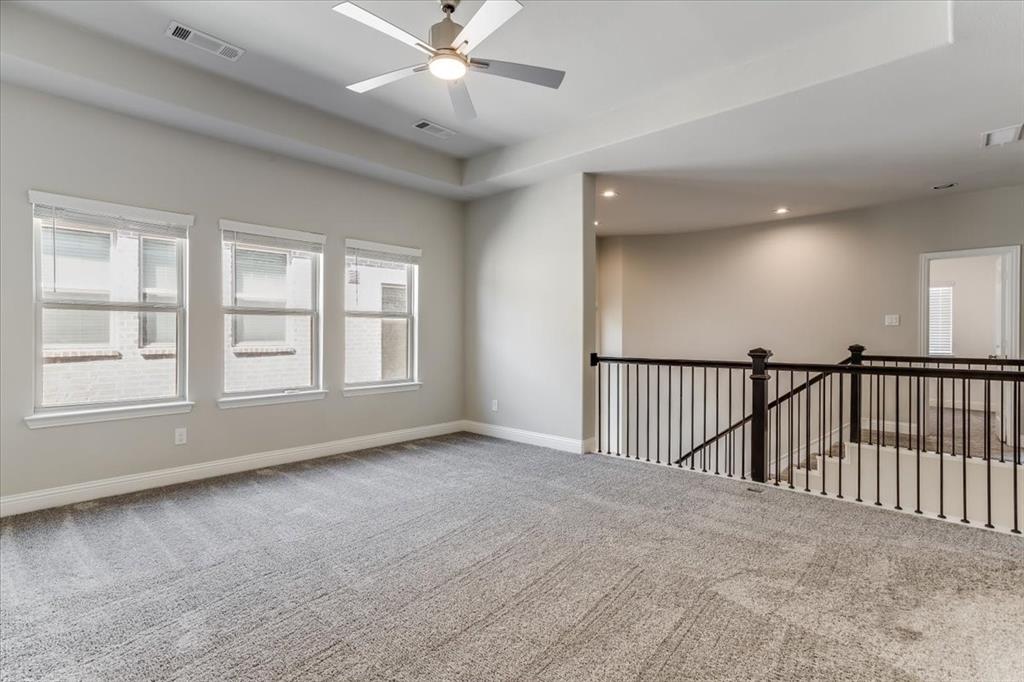 Spacious room with gray carpet flooring, multiple windows, a ceiling fan, and recessed lighting
