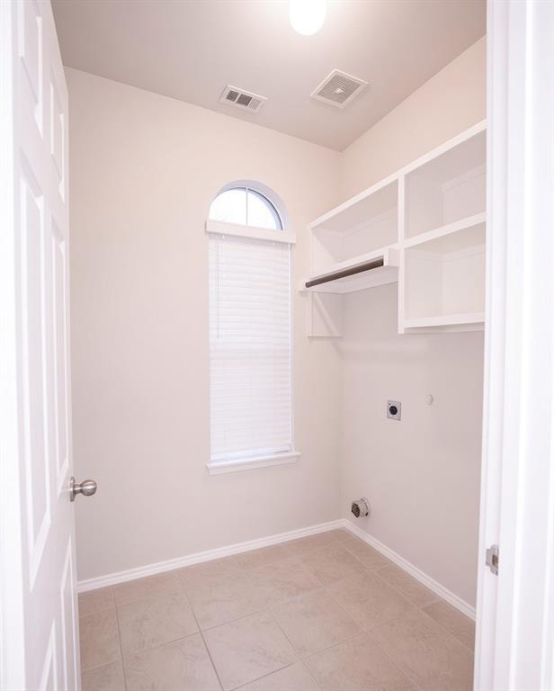 Arched window, tile flooring, built-in shelving, clothes rod, and an overhead light fixture