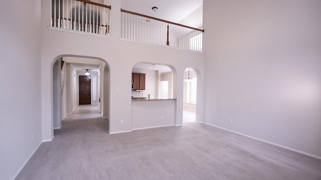Two-story living area with arched entryways, an open second-story landing, and carpet flooring