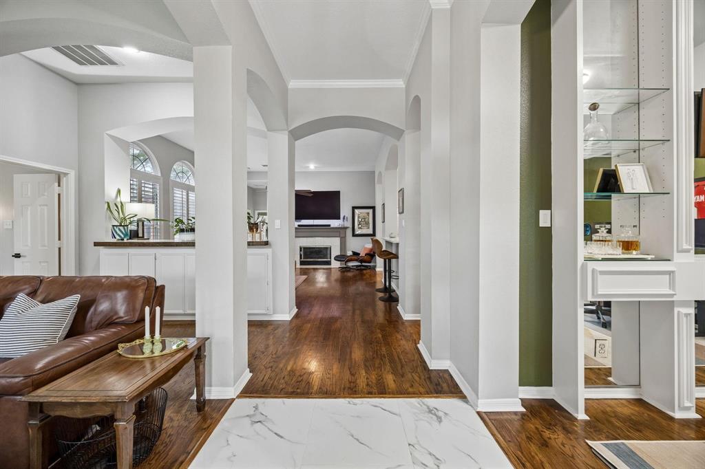 Open-concept living space featuring soaring ceilings with architectural arches, white structural columns, and rich wood-finish flooring throughout