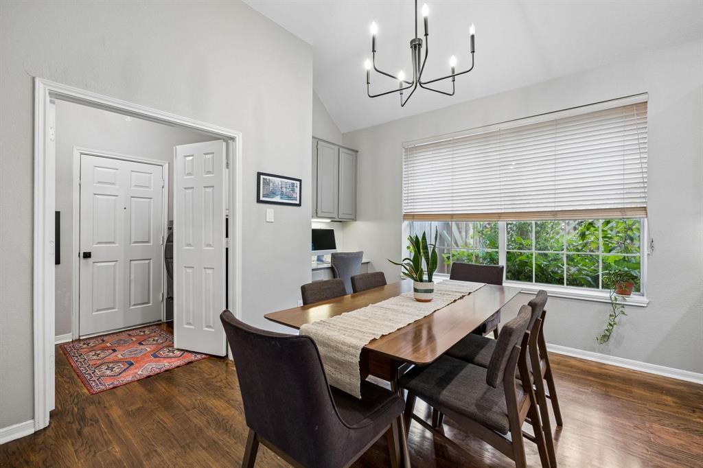 Vaulted ceiling with a chandelier, wood-finish flooring, built-in cabinetry, and a large window