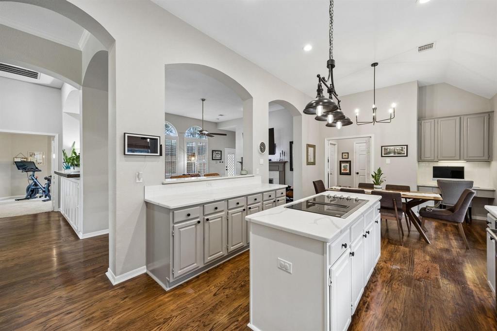 Kitchen featuring an island with a built-in cooktop, light-toned cabinetry, and dark wood-finish flooring