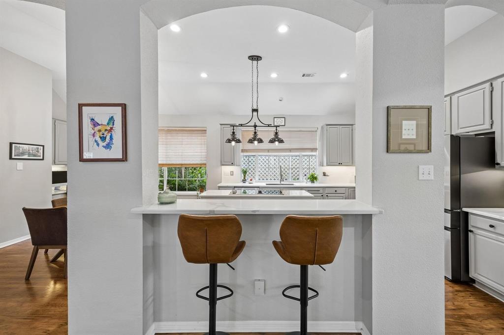 Kitchen pass-through with a breakfast bar, white countertops, gray cabinetry, and a black appliance package