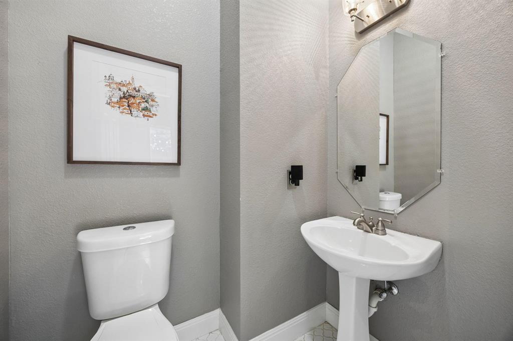 Pedestal sink with brushed nickel faucet, beveled mirror, and wall-mounted vanity lighting