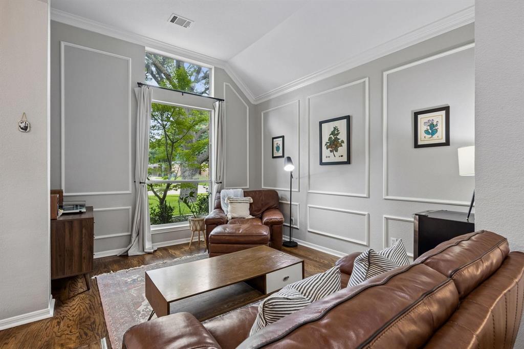 Accent wall with decorative molding, wood-finish flooring, and a large picture window