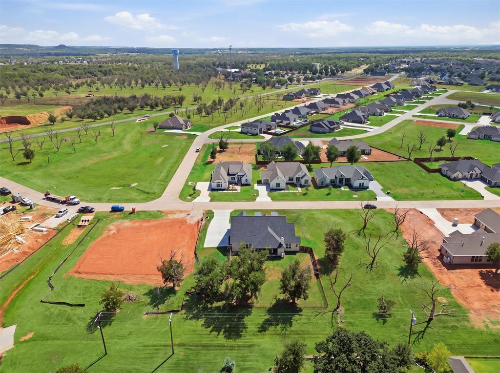 Expansive green spaces surround a newly developed residential area featuring various single-story homes and a visible water tower in the distance