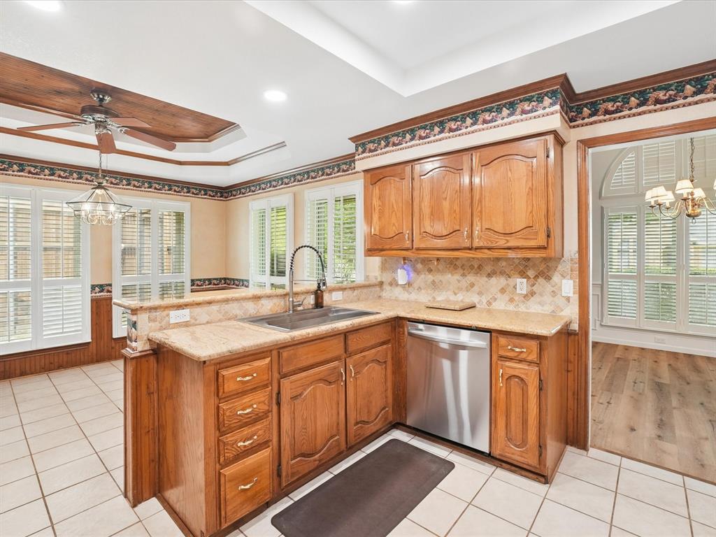 Kitchen featuring wood cabinetry, light-toned stone countertops, tile backsplash, and stainless steel appliances