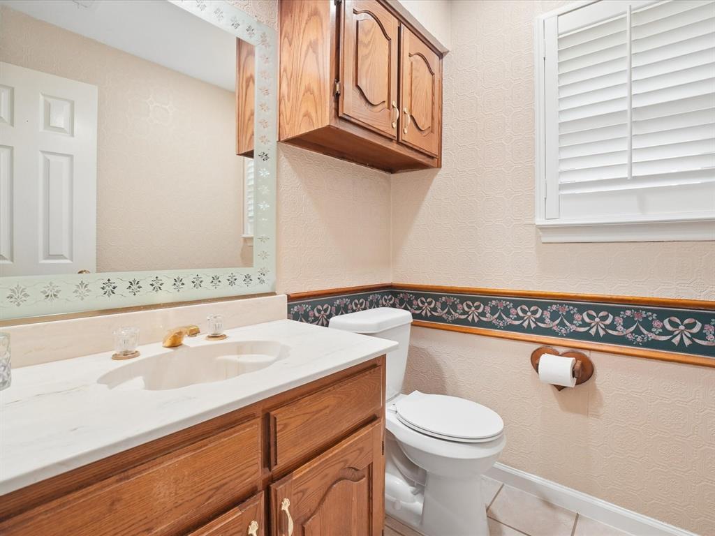 Wood-finish vanity with a light-toned countertop, under-mount sink, and brass-tone faucet