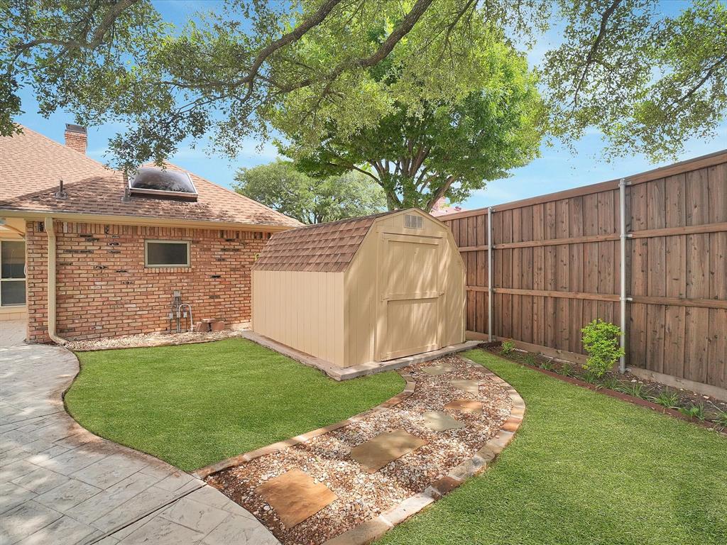 Private yard with a patterned concrete patio, a stepping stone pathway, and a wooden privacy fence