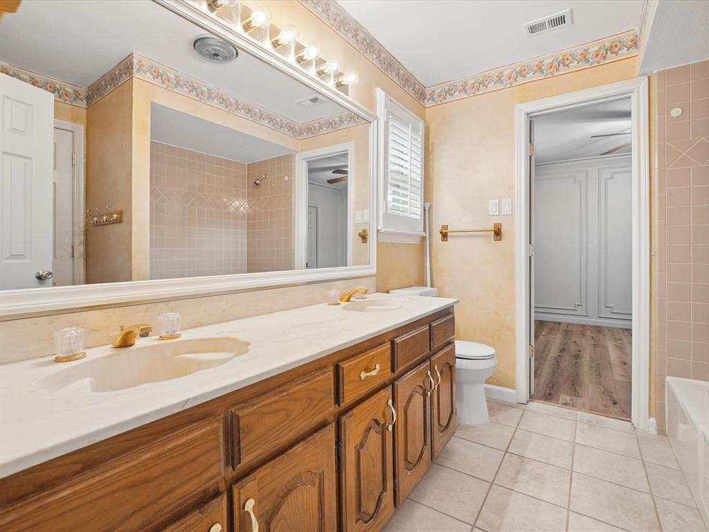 Double vanity with integrated sinks, wood-finish cabinetry, and a full-width mirror