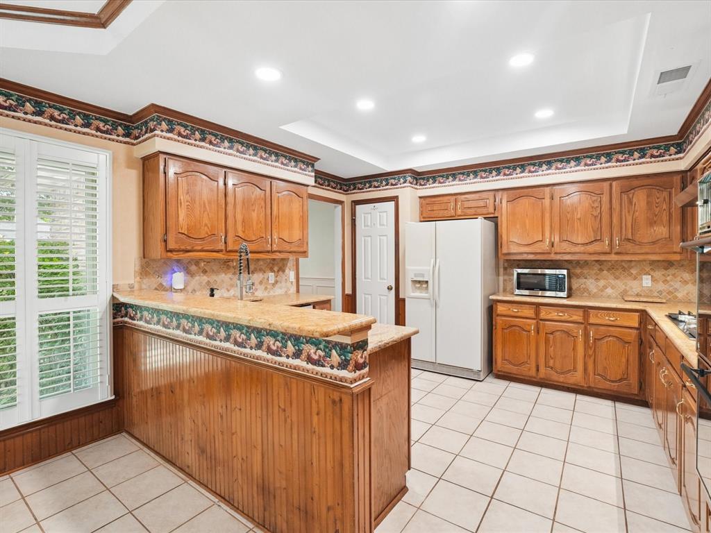 Kitchen featuring wood cabinetry, light-toned countertops, white tile flooring, and recessed ceiling lighting