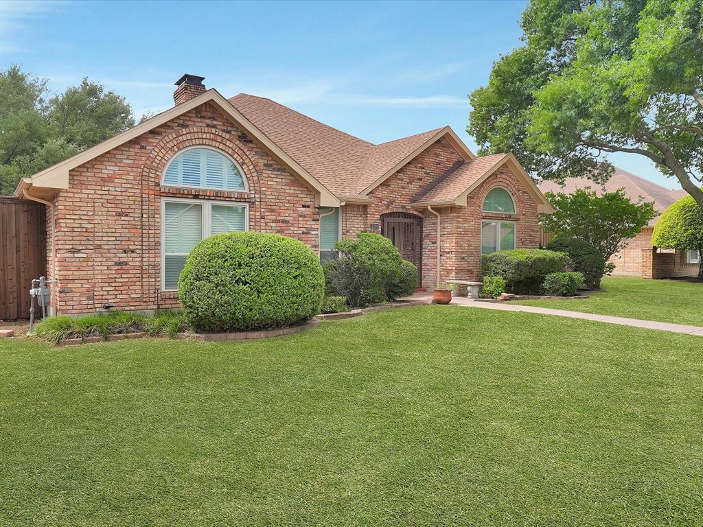 Brick exterior with arched windows, gabled roofline, and established landscaping