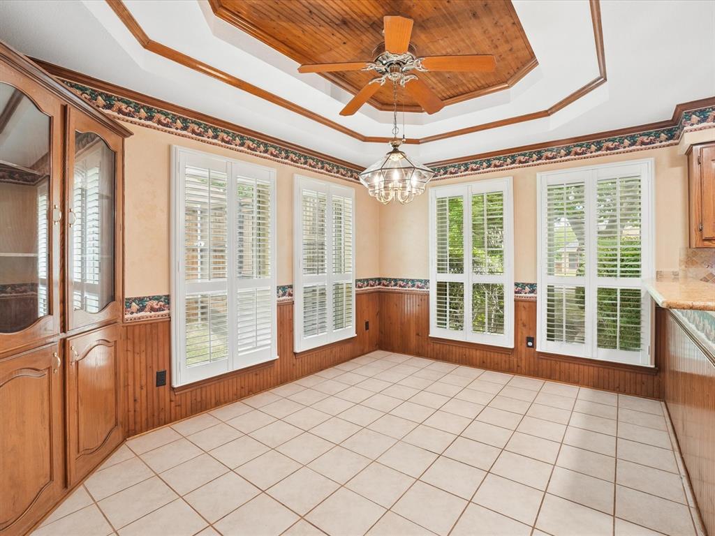 Recessed ceiling with wood-paneled inlay, ceiling fan, and chandelier