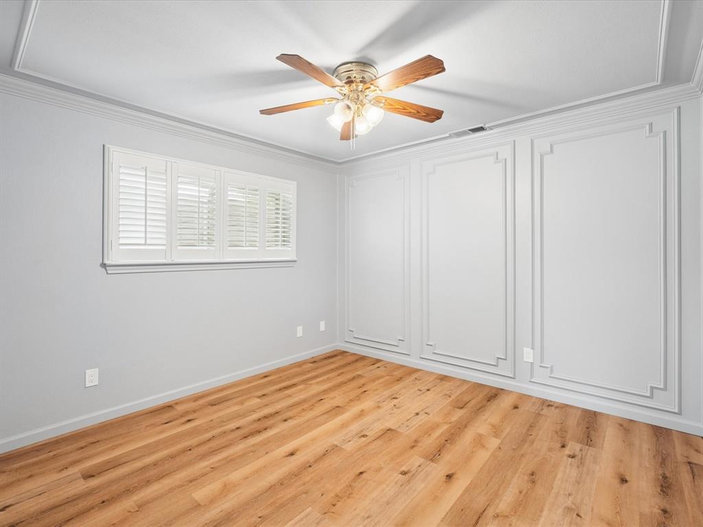 Wood-finish flooring throughout, crown molding, and decorative wall paneling