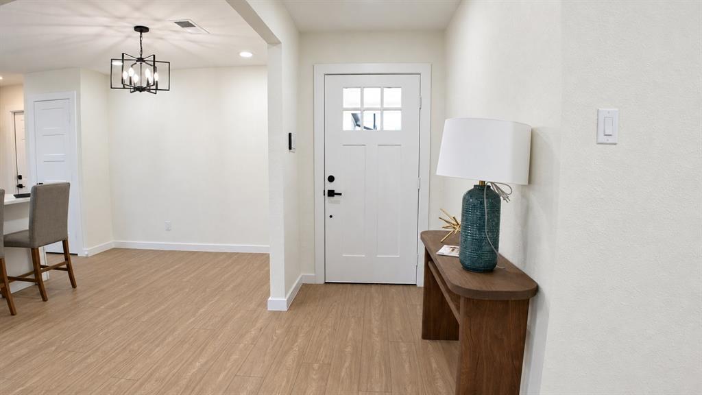 Entryway featuring a white paneled door with glass inserts, wood-finish flooring, and a contemporary black chandelier