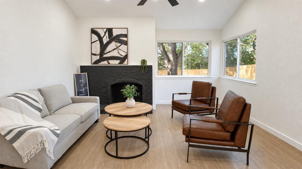 Light wood-finish flooring, white walls, and a black brick fireplace