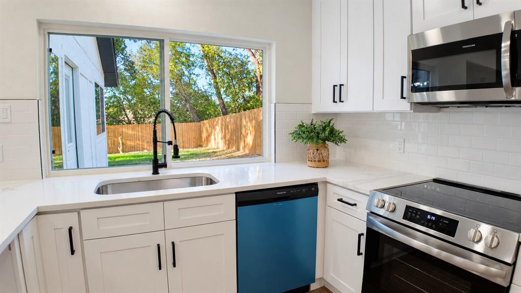 White shaker cabinetry with matte black hardware, stainless steel appliances, white subway tile backsplash, white countertops, and a stainless steel sink with a black faucet