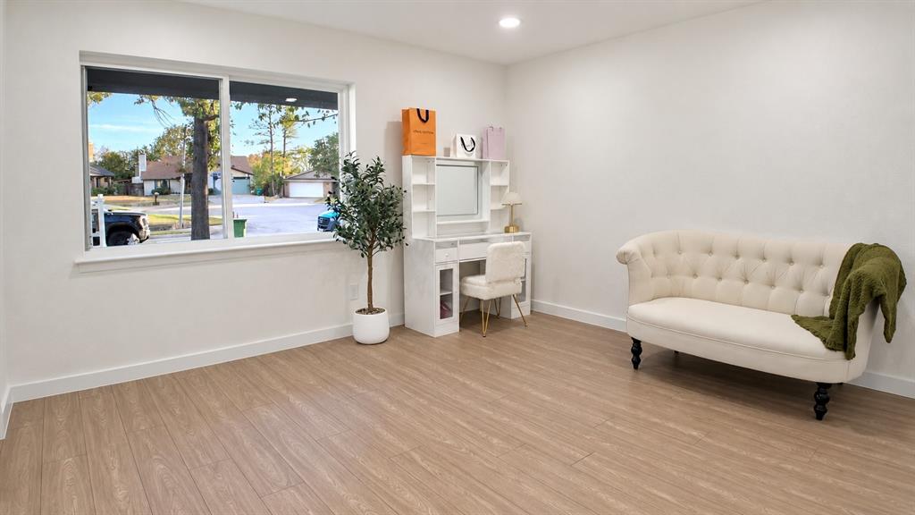 Bright room featuring wood-finish flooring, white walls, and a large window