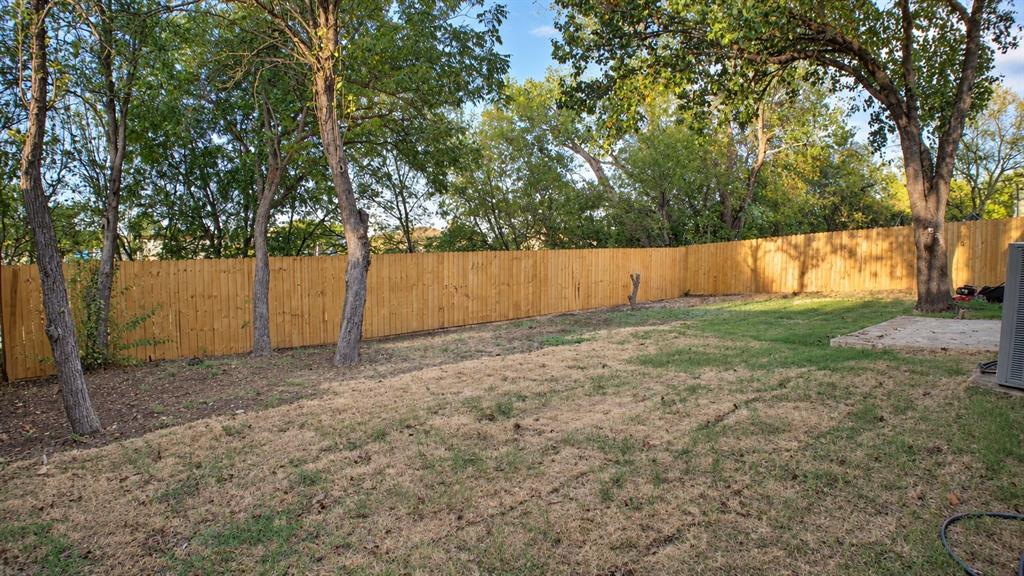 Expansive backyard featuring a wood privacy fence and mature trees