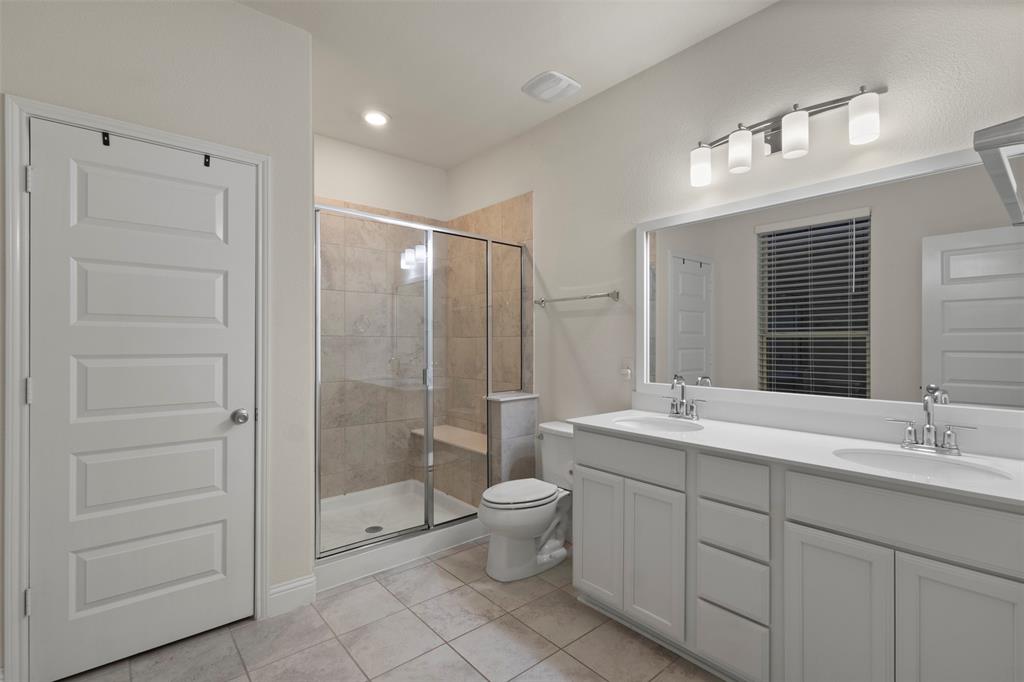 Dual vanity with white cabinetry, a large frameless mirror, and overhead lighting