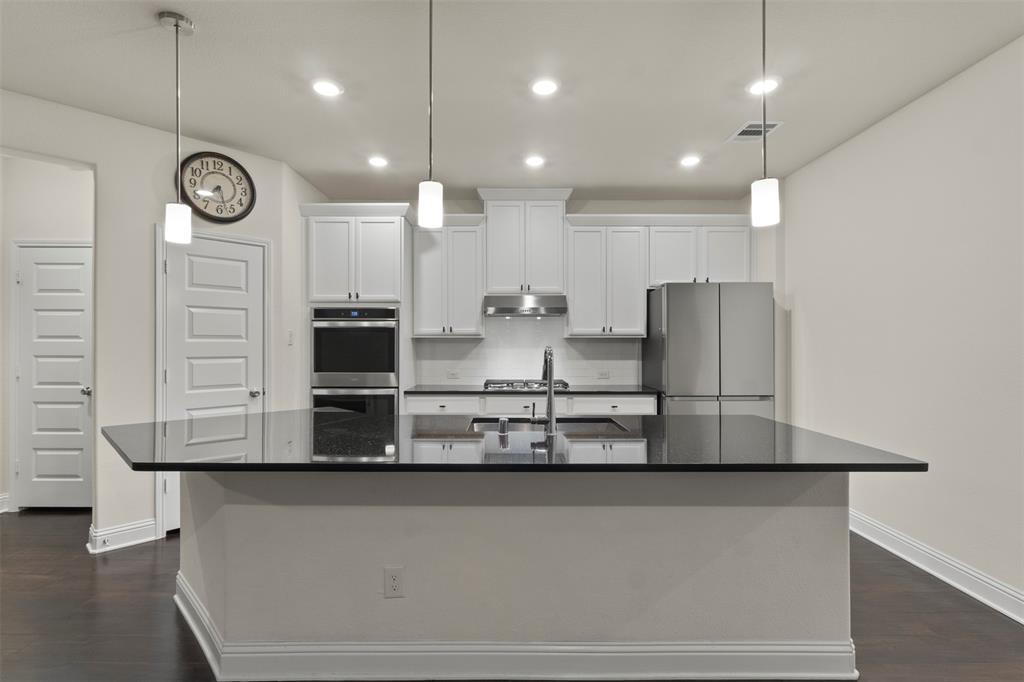 Kitchen featuring a center island with dark countertop, white shaker cabinetry, stainless steel appliances, and dark wood-finish flooring