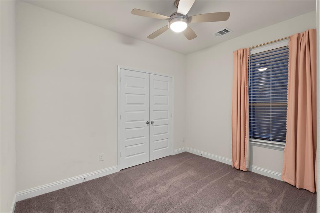 Neutral wall finishes, textured carpeting, double panel doors, and a ceiling fan with integrated lighting