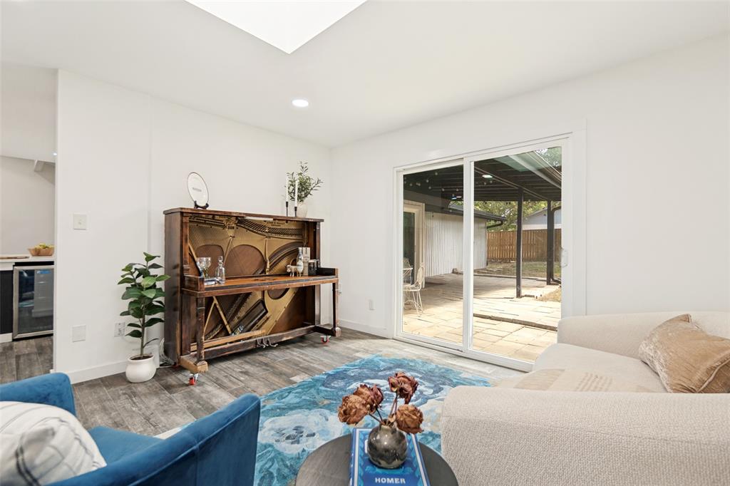 Recessed lighting, skylight, wood-finish flooring, sliding glass door, and a paved outdoor patio