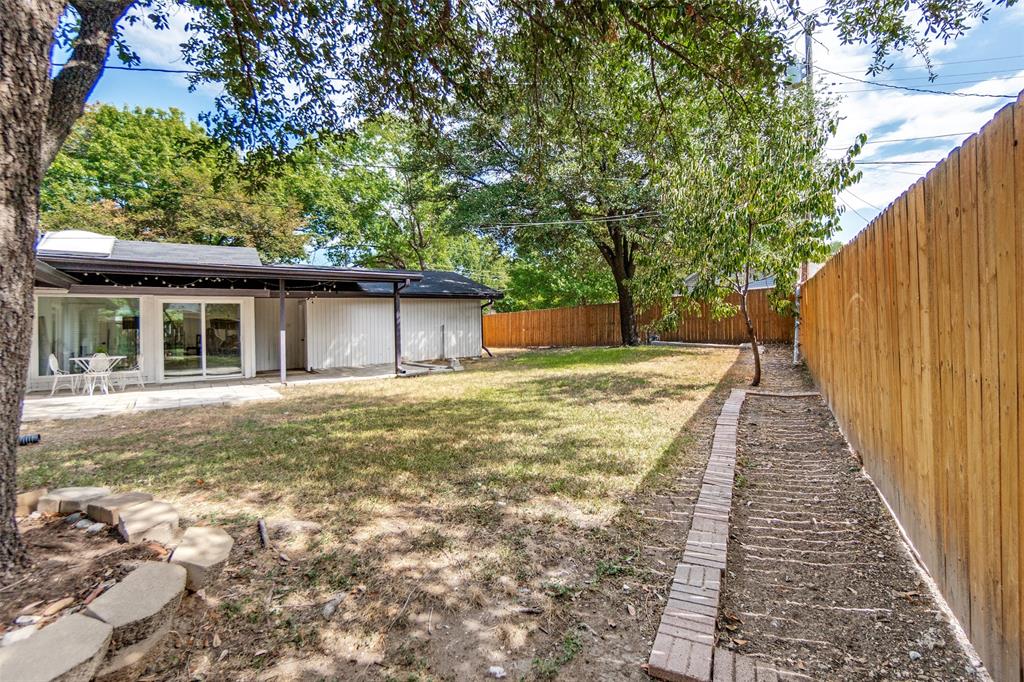 Expansive backyard featuring a privacy fence, covered patio, and large sliding glass doors