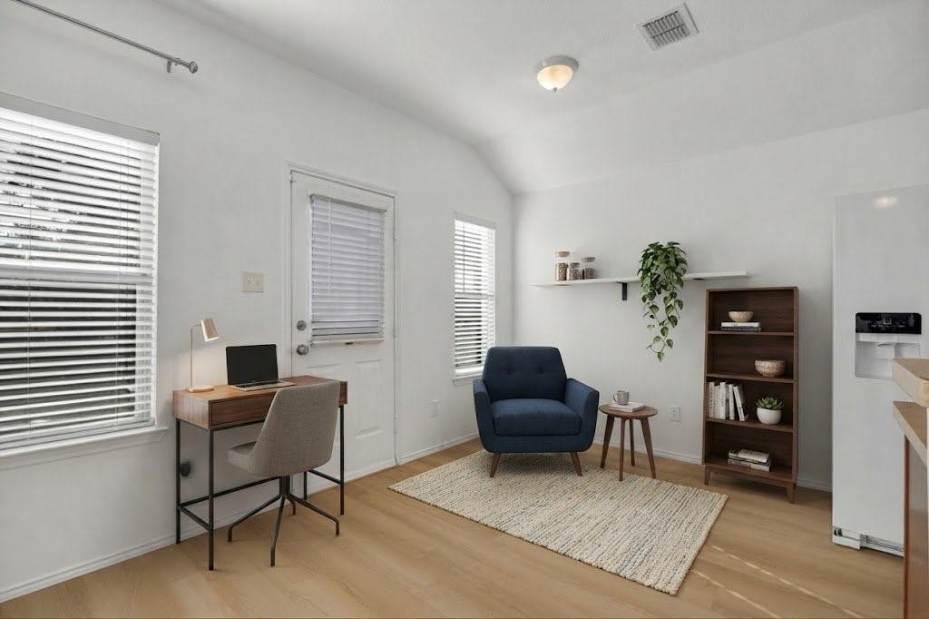 Light wood-finish flooring, white walls, and multiple windows with blinds