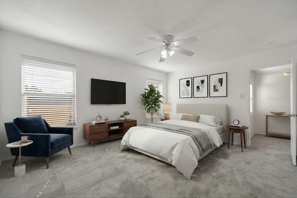 Plush carpeting throughout, ceiling fan with integrated lighting, multiple windows with blinds, and white painted walls