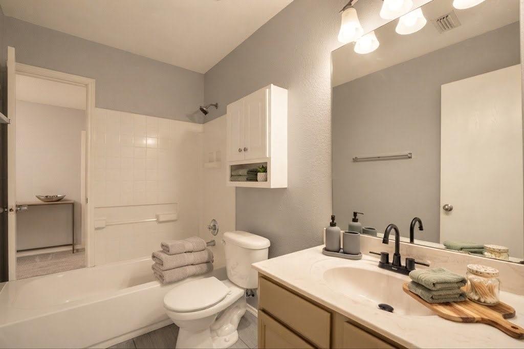 Bathroom featuring a single vanity with an integrated sink, matte black faucet, and a wall-mounted mirror