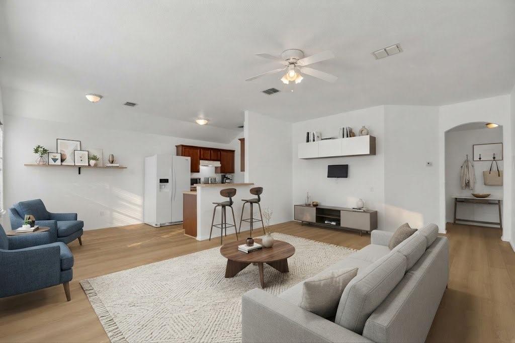 Open-concept living area featuring wood-finish flooring, a ceiling fan with integrated lighting, and recessed lighting