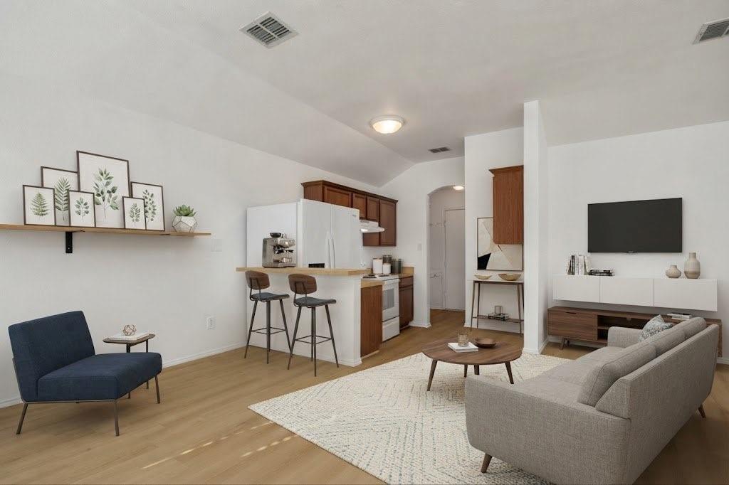 Open-concept living area with wood-finish flooring, vaulted ceiling, and recessed lighting