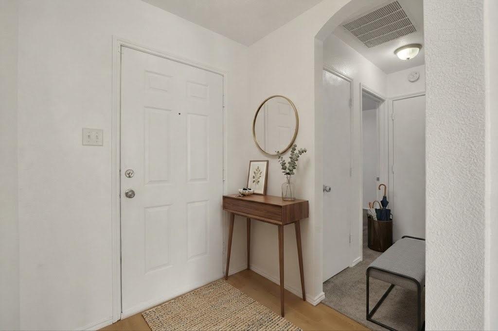 Light wood-finish flooring with a white paneled door and archway