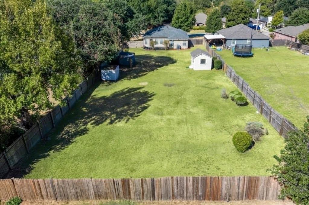 Expansive fenced yard featuring a storage shed and mature trees