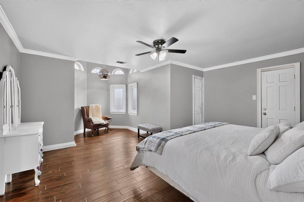 Wood-finish flooring, multi-pane arched windows, recessed lighting, crown molding, and a multi-blade ceiling fan