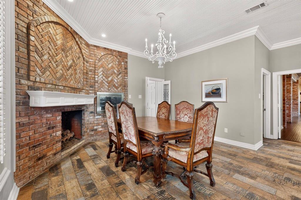 Floor-to-ceiling brick fireplace with arched herringbone inlay, wood-finish flooring, beadboard ceiling, and decorative iron chandelier