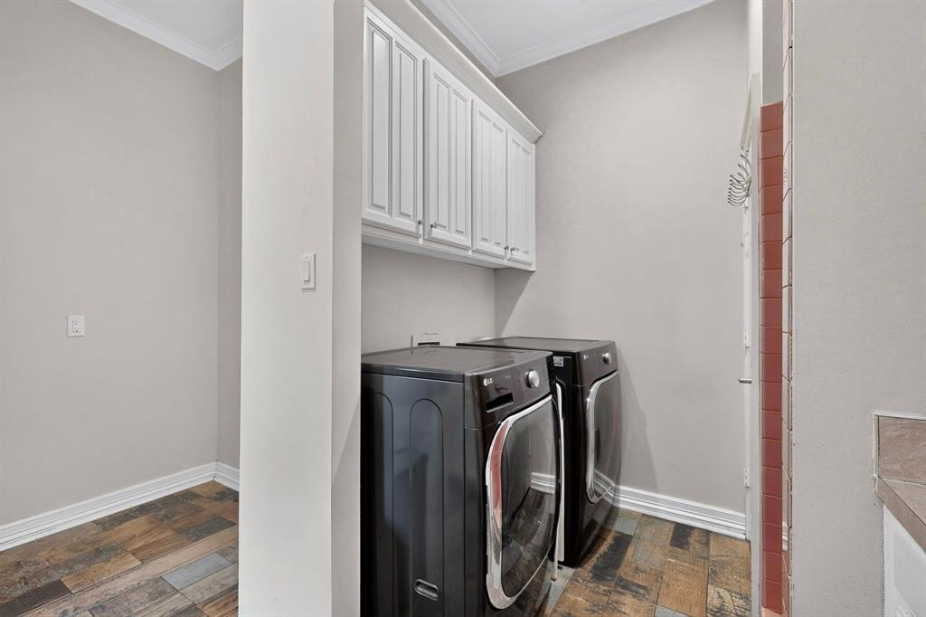 Laundry area featuring wood-finish tile flooring, white shaker-style wall-mounted cabinetry, and crown molding